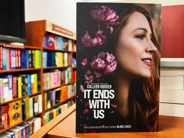 Lviv, Ukraine - February 20, 2025: A displayed It Ends With Us by Colleen Hoover book with vibrant cover art, in a library environment. clipart