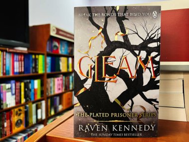 Lviv, Ukrayna - 20 Şubat 2025: Raven Kennedy 'nin' Gleam 'kitabı bir kitapçıda renkli kitaplıklara karşı hazırlanmıştır