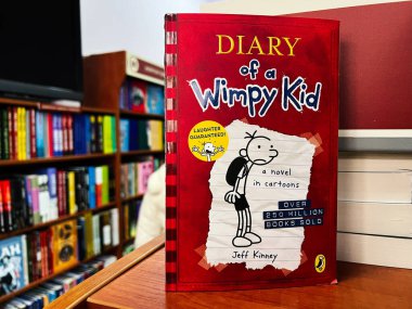 Lviv, Ukraine - February 20, 2025: Diary of a Wimpy Kid by Jeff Kinney displayed among books in a library. clipart