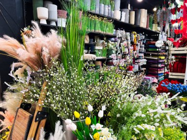 Renkli el sanatları malzemeleri ve dekoratif çiçekler rahat bir dükkan ortamında raflarda dizilmiş..