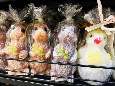 Tavşan ve civciv şeker figürleri bir rafta sergileniyor, şeffaf plastik torbalara sarılmış..