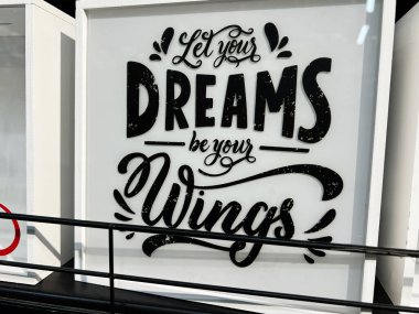 Hayallerin kanatların olsun. Dekoratif duvar sanatı, hayalleri ve kendine güveni destekleyen motive edici bir alıntı sergiliyor.