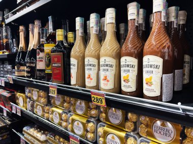 Kyiv, Ukraine - February 26, 2025: Dalcowski alcohol and Ferrero Rocher candy products showcased neatly on supermarket shelves clipart