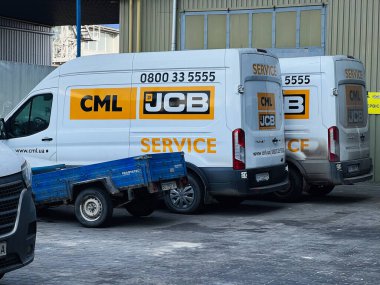 Kyiv, Ukrayna - 26 Şubat 2025: Markalı logoları ve karavanları olan sanayi bölgesinde servis JCB kamyonları, şehir peyzajı.