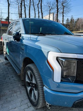 Kyiv, Ukrayna - 26 Şubat 2025: Güneşli bir günde ağaçlarla çevrili mavi bir Ford F-150 kamyonet dışarıda duruyor.