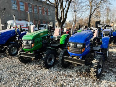 Kyiv, Ukrayna - 26 Şubat 2025: Açık alandaki çakıl taşı yüzeyinde çeşitli parlak ve modern küçük traktörler sergilendi