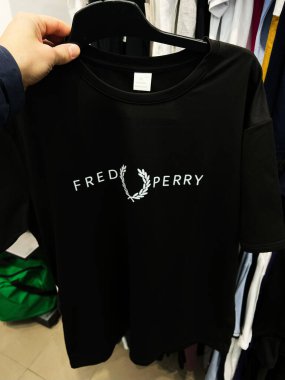 Kyiv, Ukrayna - 27 Şubat 2025: Bir elbise mağazasında askıda sergilenen siyah damgalı Fred Perry tişörtü.