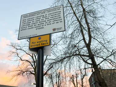 Londra, İngiltere - 02 Mart 2025: Akşam gökyüzü ve verimsiz ağaçlara karşı taksisiz bekleme tabelasının kapatılması.