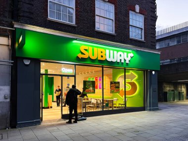 Londra, İngiltere - 02 Mart 2025: Aydınlatılmış Metro IP LLC mağazası akşam saatlerinde görünür tabela ve müşterilerle birlikte