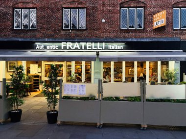 Londra, İngiltere - 02 Mart 2025: Charming Fratelli İtalyan restoranı ön tarafı açık hava oturma, akşam ışığı altında aydınlatma.