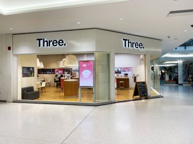 Londra, İngiltere - 02 Mart 2025: Parlak ışıklı bir alışveriş merkezinde üç işaretli bir telekomünikasyon mağazası 