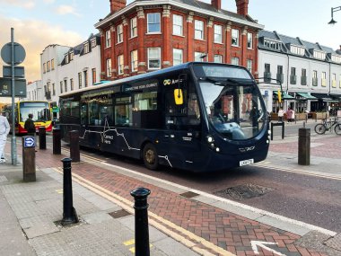 Londra, İngiltere - 02 Mart 2025: Perakende mağazaları ve binalarla çevrili bir şehir caddesi boyunca seyahat eden bir şehir otobüsü.