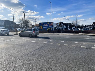 Londra, İngiltere - 02 Mart 2025: Mavi gökyüzünün altında arabaların, yayaların ve reklam tabelalarının olduğu bir şehir caddesinin görüntüsü