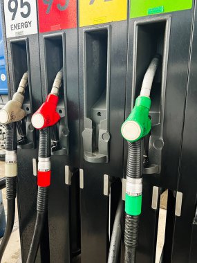 Kyiv, Ukrayna - 04 Mart 2025: Yağmurlu bir günde modern benzin istasyonu ekipmanlarını tasvir eden renkli yakıt pompası başlıkları.