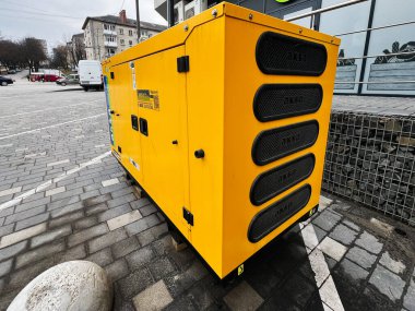 Kyiv, Ukrayna - Mart 04, 2025: Taşlı ve kaldırımlı kentsel bir ortama yüklü büyük sarı Aksa jeneratörü.