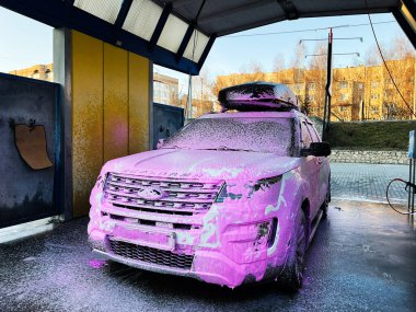 Kyiv, Ukrayna - Mart 04, 2025: Büyük Ford Explorer SUV açık hava oto yıkama işleminde pembe köpükle kaplanmış
