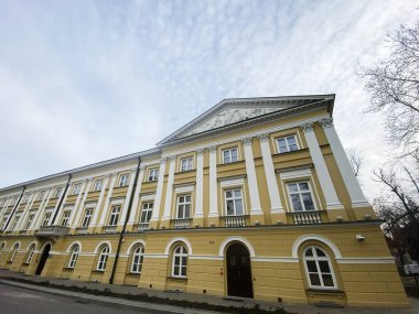 Polonya 'nın Varşova şehrinde bulutlu bir gökyüzü altında karmaşık mimari sergilenen tarihi klasik üniversite binası.