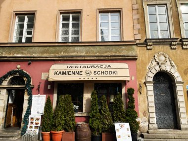 Varşova, Polonya - 09 Mart 2025 Varşova Kamienne Schodki restoranının manzarası yeşillik ve büyüleyici bir mimari görünüme sahip.