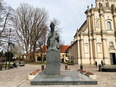 Varşova, Polonya - 09 Mart 2025: Stefan Wyszynski Anıtı. Varşova Polonya 'da tarihi kilise ve arka planda ağaçlarla çevrili bir heykel