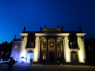 Varşova, Polonya - 24 Nisan 2024: Klasik Lazienki Sarayı yapısı açık, derin mavi bir gökyüzü altında akşamleyin aydınlandı. Varşova, Polonya