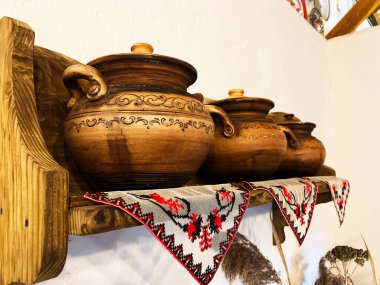 Taşralı ahşap raflarda zanaatkar seramik kaplar işlenmiş kumaşlarla süslenir.