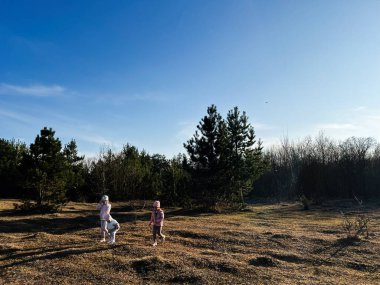 İki çocuk açık gökyüzünün altındaki huzurlu bir ormanda açık hava aktivitelerinin keyfini çıkarıyorlar.