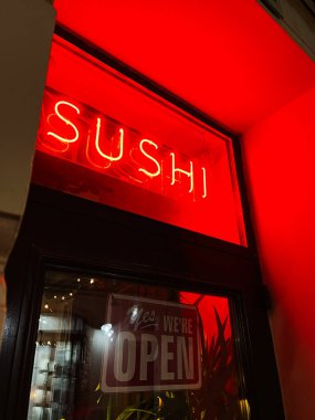 Lviv, Ukrayna - 12 Mart 2025: Vibrant neon suşi işareti ve açık tabela çağdaş restoran girişinin önünde sergilenmektedir
