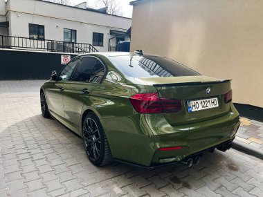 Kyiv, Ukrayna - 12 Mart 2025: Şık yeşil BMW 3 serisi sedan araç modern bir binanın yakınındaki kentsel alana park edilmiş