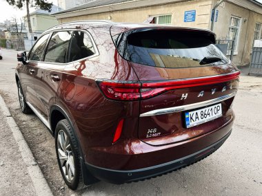 Kyiv, Ukrayna - 12 Mart 2025: Haval H6 model kestane rengi bir SUV eski bir binanın yanına park edilmiş. 