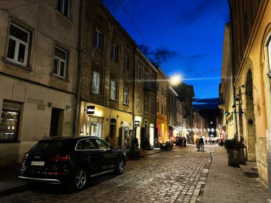 Lviv, Ukrayna - 12 Mart 2025: Dükkanlar, kaldırım taşları ve canlı akşam atmosferinin yer aldığı büyüleyici bir şehir caddesi