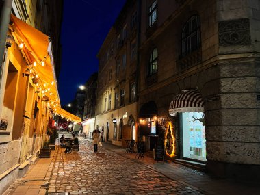 Lviv, Ukrayna - 12 Mart 2025: Tarihi binalarla çevrili aydınlık bir kaldırım taşının gece manzarası.