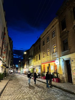 Lviv, Ukrayna - 12 Mart 2025 Parlayan ışıkları ve geceleri gezinen insanlarla dolu canlı bir kaldırım taşı caddesi.