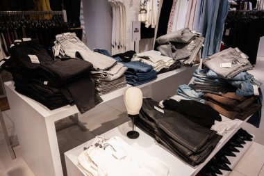 Lviv, Ukrayna - 13 Mart 2025: Moda bir perakende mağazasında çeşitli üst üste dizilmiş kot pantolonlar sergileniyor