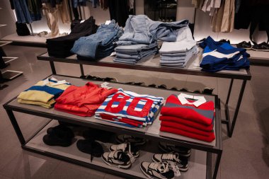 Lviv, Ukrayna - 13 Mart 2025: Bir mağaza vitrininde düzenlenmiş kot, gömlek ve spor ayakkabısı koleksiyonu