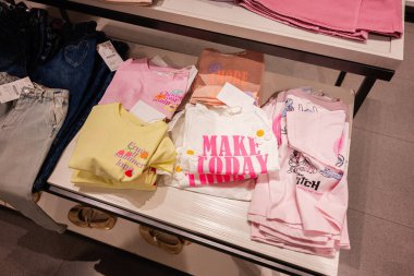 Lviv, Ukrayna - 13 Mart 2025: Parlak renkli renkli tişörtler yakındaki kot pantolonlarla birlikte perakende masasında düzenlendi