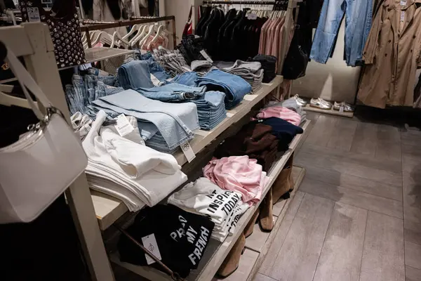 Lviv, Ukrayna - 16 Mart 2025: Modern bir perakende mağazasında şık bir alışveriş için raflara dizilmiş giyim ürünleri.