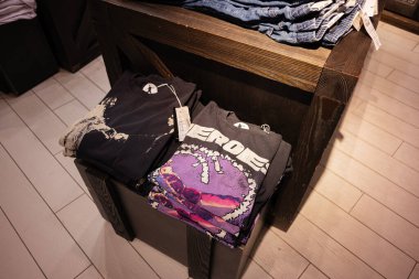 Lviv, Ukrayna - 16 Mart 2025: Modern bir perakende satış ortamında gösterilen katlanmış grafik tişört koleksiyonu.