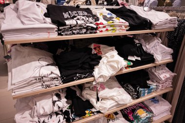 Lviv, Ukrayna - 16 Mart 2025: Ahşap perakende raflarında belirgin şekilde sergilenen çeşitli tasarımların yer aldığı tişörtler