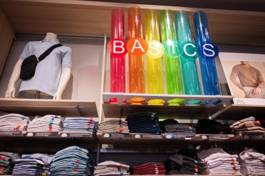 Lviv, Ukrayna - 16 Mart 2025: Sergilenen gömlekli manken, katlanmış giysi raflarda ve renkli tabela