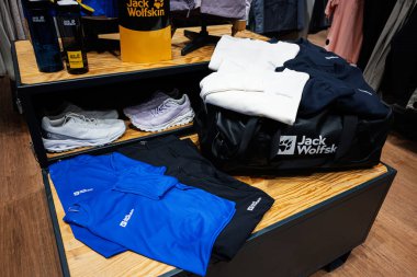Lviv, Ukrayna - 17 Mart 2025: Jack Wolfskin giysi, ayakkabı ve markalı aksesuarları ahşap ekranda gösteren perakende düzenleme.