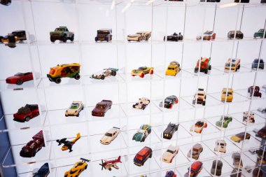 Lviv, Ukrayna - 19 Mart 2025: Renkli Hot Wheels minyatür oyuncak arabaları beyaz ışık altında organize cam bir rafta sergileniyor.