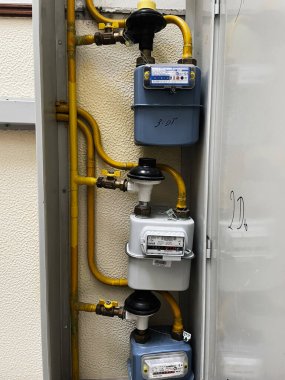 Fatima, Portekiz - 20 Aralık 2023: Alçılı bir duvardaki sarı borularla birbirine bağlı üç konut gaz metresi