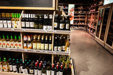 Lviv, Ukrayna - 25 Mart 2025: İyi aydınlatılmış bir süpermarkette ahşap raflarda sergilenen şaraplar.