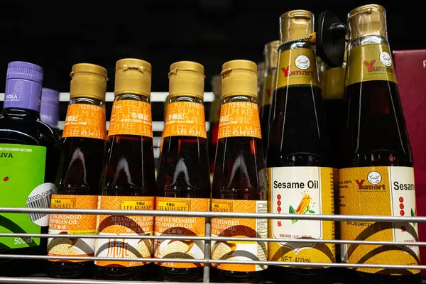 Lviv, Ukrayna - 25 Mart 2025: Çeşitli Lee Kum Kee harmanlanmış susam yağı şişeleri bir mağaza rafında güzelce yerleştirildi