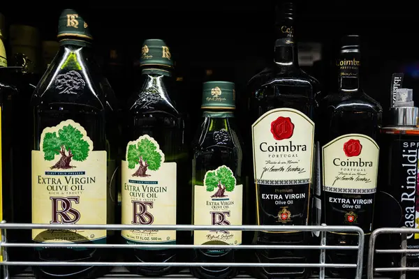 Lviv, Ukrayna - 25 Mart 2025: Bir mağaza rafında düzgünce dizilmiş çeşitli ekstra bakire zeytinyağı şişeleri