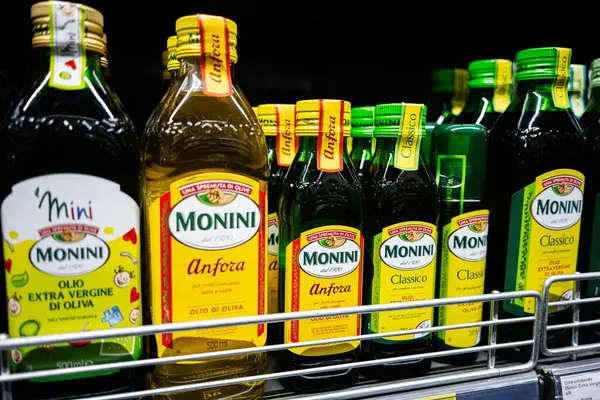 Lviv, Ukrayna - 25 Mart 2025: Bir süpermarket rafında arka arkaya dizilmiş çeşitli Monini zeytinyağı şişeleri.