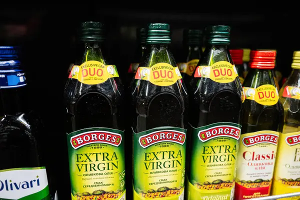 Lviv, Ukrayna - 25 Mart 2025: Bir perakende mağazasında düzgünce düzenlenmiş ekstra bakire zeytinyağı şişeleri.