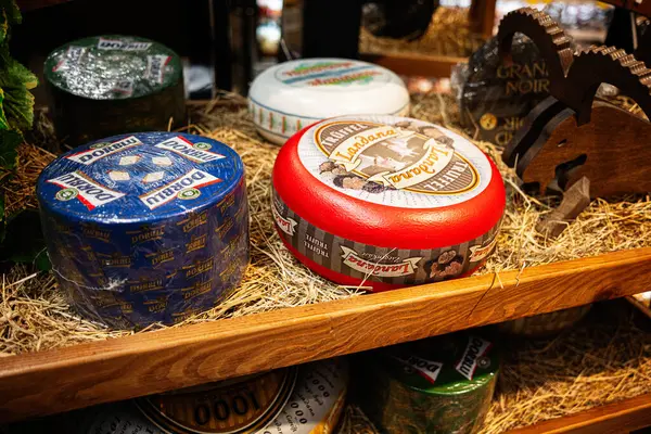 Lviv, Ukrayna - 25 Mart 2025: Samandan dekore edilmiş ahşap bir rafta çeşitli renkli peynir çarkları,.