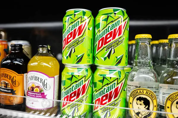 Lviv, Ukrayna - 25 Mart 2025: Aydınlatılmış bir soğutma vitrininde sergilenen çeşitli içecek kutuları ve şişeleri.