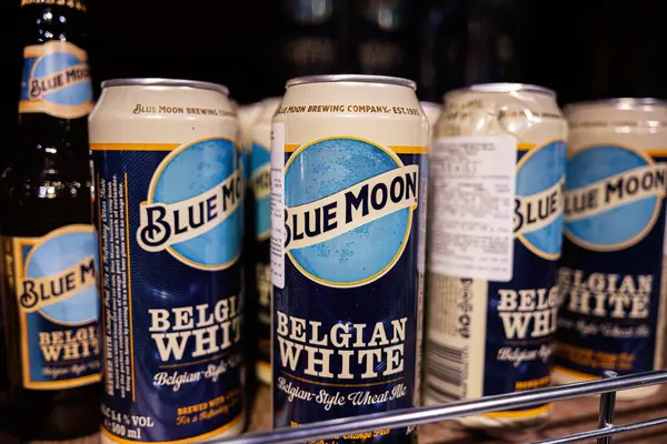Lviv, Ukrayna - 25 Mart 2025: Mavi Ay Belçika Beyaz bira kutuları ticari bir perakende satış rafında sergilendi.